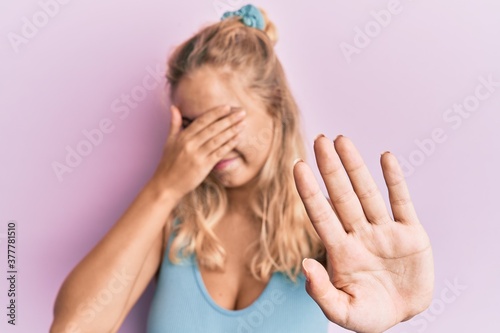 Young blonde girl wearing casual clothes covering eyes with hands and doing stop gesture with sad and fear expression. embarrassed and negative concept.