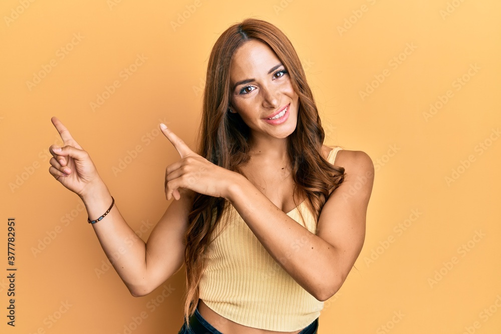 Young brunette woman wearing casual clothes smiling and looking at the camera pointing with two hands and fingers to the side. Young brunette woman wearing casual clothes smiling and looking at the camera pointing with two hands and fingers to the side.