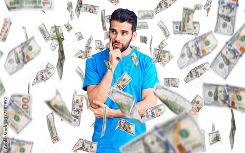 Young handsome man with beard wearing casual t-shirt serious face thinking about question with hand on chin, thoughtful about confusing idea photo