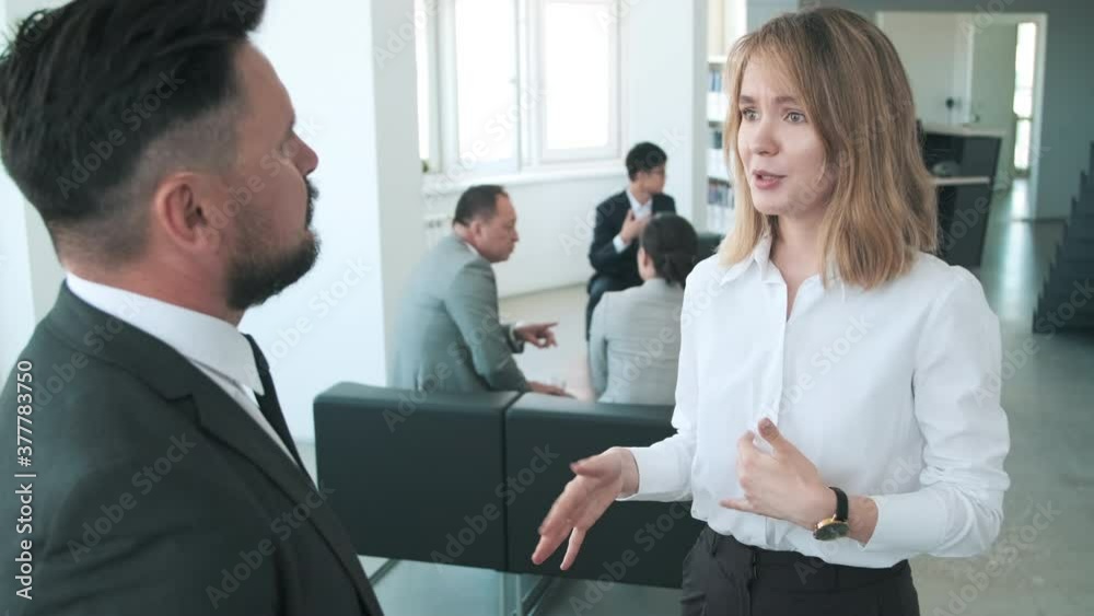 Active young woman standing with her mature male colleague in office room sharing her ideas about work plan Active young woman standing with her mature male colleague in office room sharing her ideas about work plan