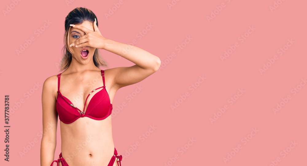 Young beautiful woman wearing bikini peeking in shock covering face and eyes with hand, looking through fingers with embarrassed expression. Young beautiful woman wearing bikini peeking in shock covering face and eyes with hand, looking through fingers with embarrassed expression.
