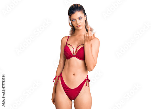 Young beautiful woman wearing bikini showing middle finger, impolite and rude fuck off expression © Krakenimages.com
