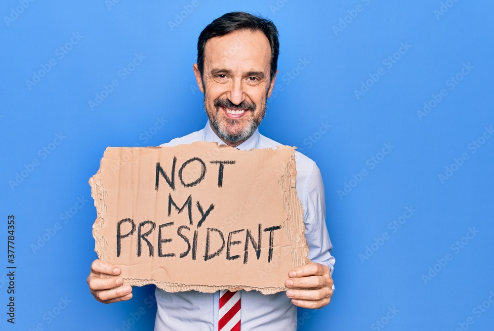 Middle age business man asking for political holding banner with not my president message looking positive and happy standing and smiling with a confident smile showing teeth Middle age business man asking for political holding banner with not my president message looking positive and happy standing and smiling with a confident smile showing teeth