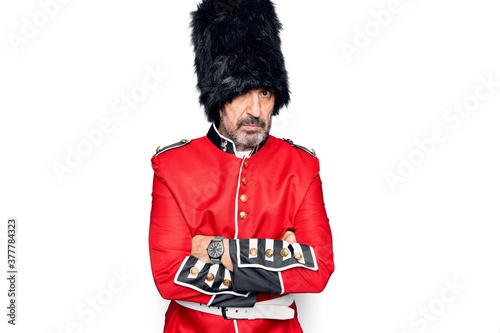 Middle age handsome wales guard man wearing traditional uniform over white background skeptic and nervous, disapproving expression on face with crossed arms. Negative person.