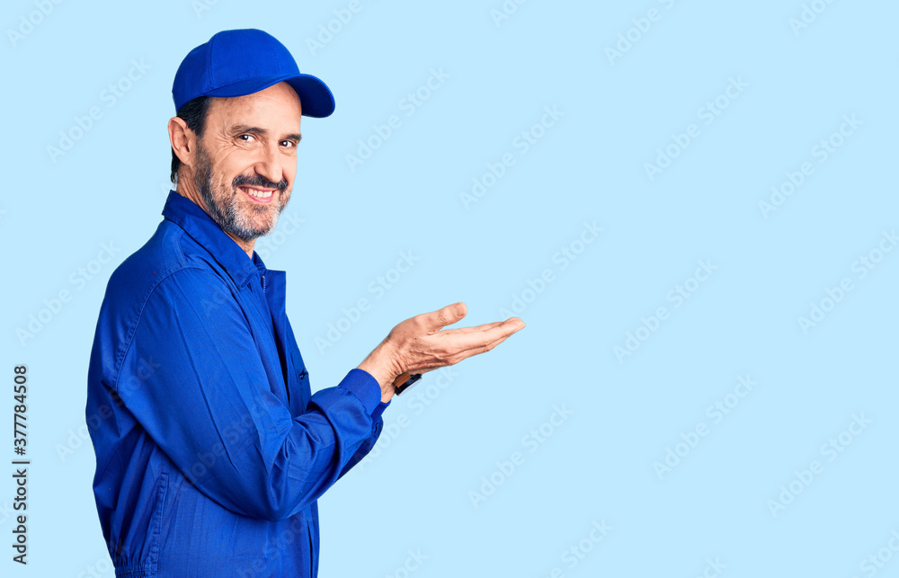 Middle age handsome man wearing mechanic uniform pointing aside with hands open palms showing copy space, presenting advertisement smiling excited happy Middle age handsome man wearing mechanic uniform pointing aside with hands open palms showing copy space, presenting advertisement smiling excited happy