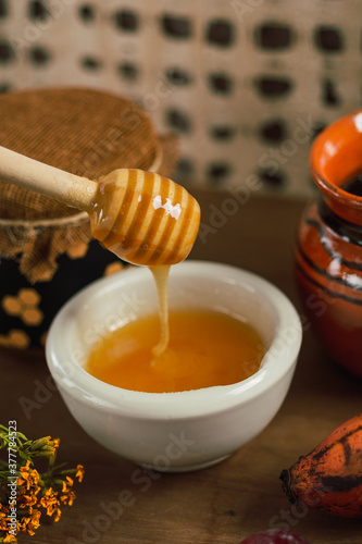 Detail of container with honey, next to cup of coffee and red bananas