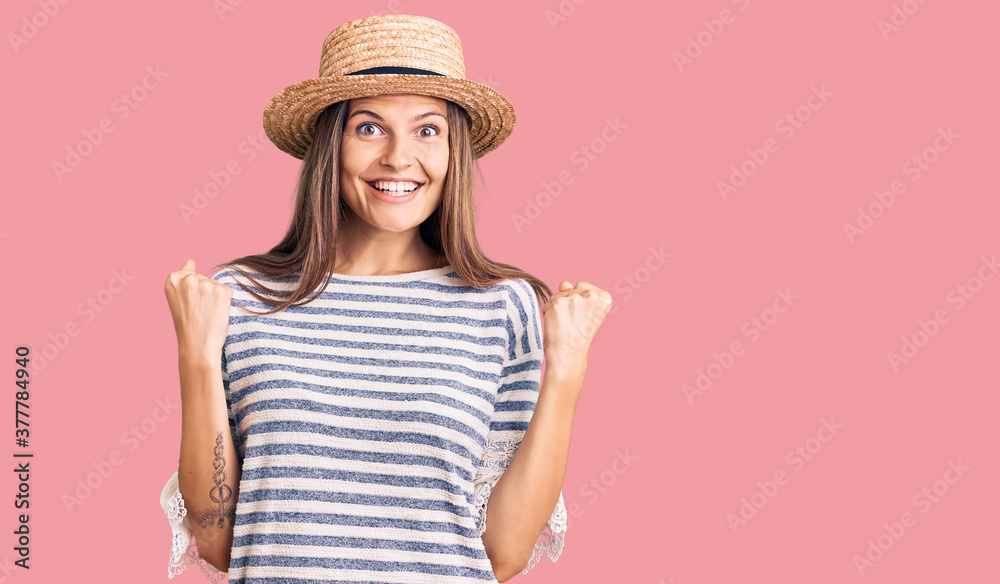 Beautiful caucasian woman wearing summer hat celebrating surprised and amazed for success with arms raised and open eyes. winner concept.