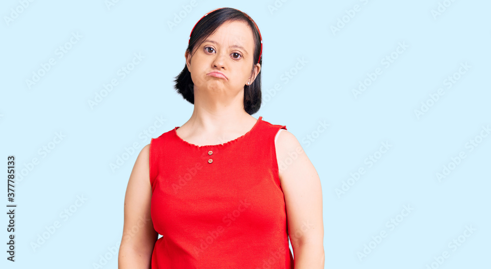 Brunette woman with down syndrome wearing casual clothes with serious expression on face. simple and natural looking at the camera. Brunette woman with down syndrome wearing casual clothes with serious expression on face. simple and natural looking at the camera.