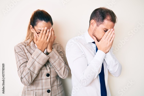 Beautiful couple wearing business clothes with sad expression covering face with hands while crying. depression concept.