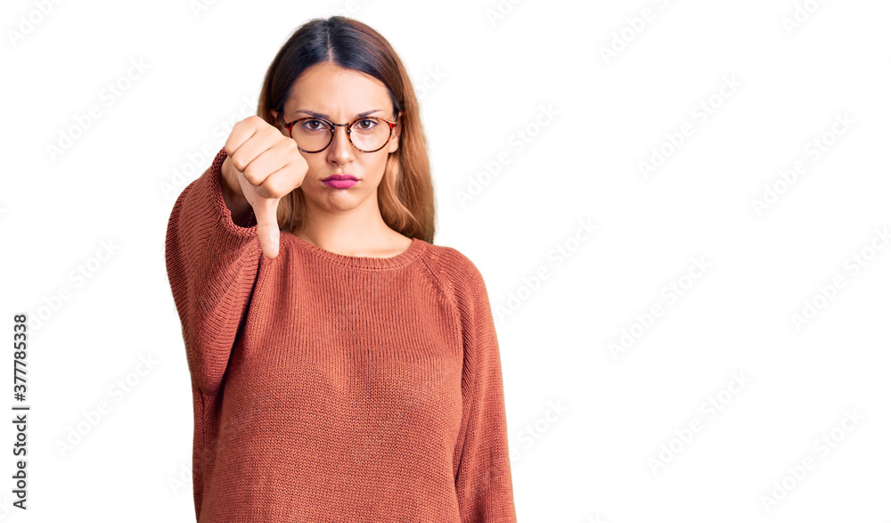 Beautiful young woman wearing casual clothes and glasses looking unhappy and angry showing rejection and negative with thumbs down gesture. bad expression.