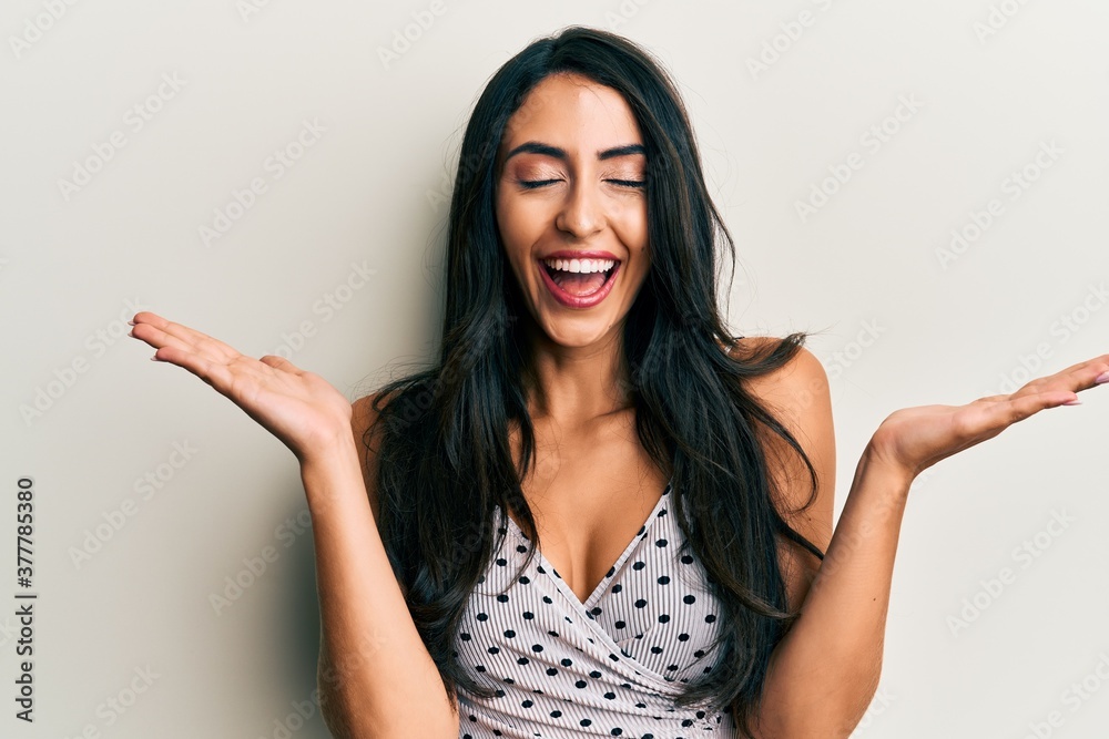 Beautiful hispanic woman wearing casual clothes celebrating mad and crazy for success with arms raised and closed eyes screaming excited. winner concept Beautiful hispanic woman wearing casual clothes celebrating mad and crazy for success with arms raised and closed eyes screaming excited. winner concept