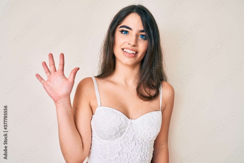 Brunette teenager girl posing elegant showing and pointing up with fingers number five while smiling confident and happy. Brunette teenager girl posing elegant showing and pointing up with fingers number five while smiling confident and happy.