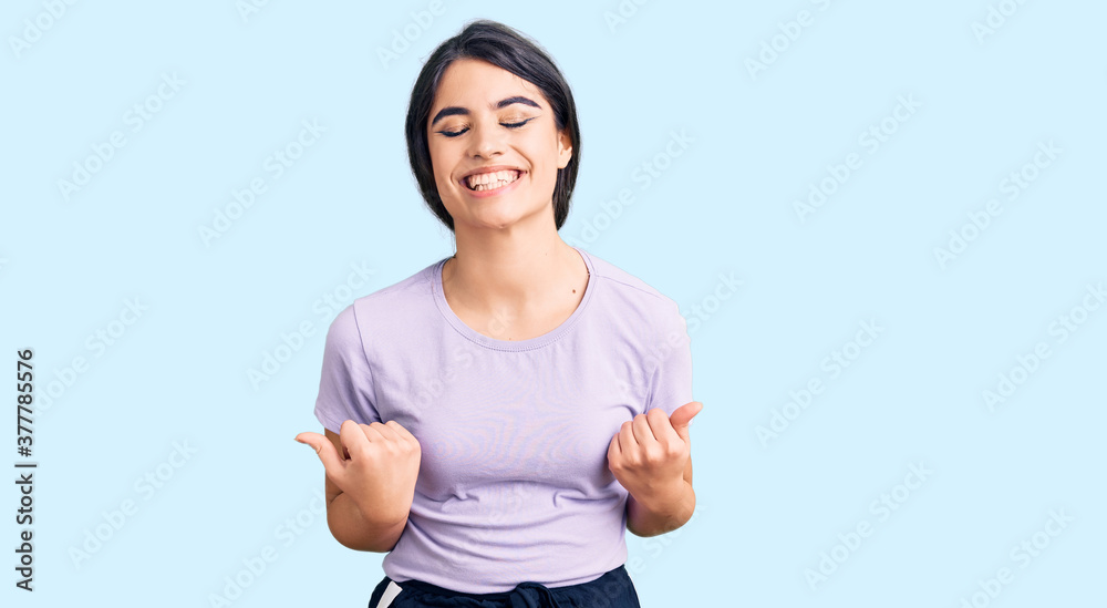 Brunette teenager girl wearing casual clothes very happy and excited doing winner gesture with arms raised, smiling and screaming for success. celebration concept. Brunette teenager girl wearing casual clothes very happy and excited doing winner gesture with arms raised, smiling and screaming for success. celebration concept.