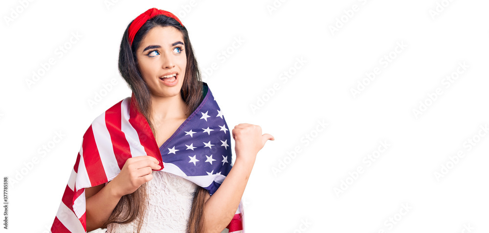 Brunette teenager girl holding united states flag pointing thumb up to the side smiling happy with open mouth Brunette teenager girl holding united states flag pointing thumb up to the side smiling happy with open mouth