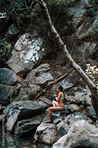 Chica joven atractiva en lago posando sobre una piedra