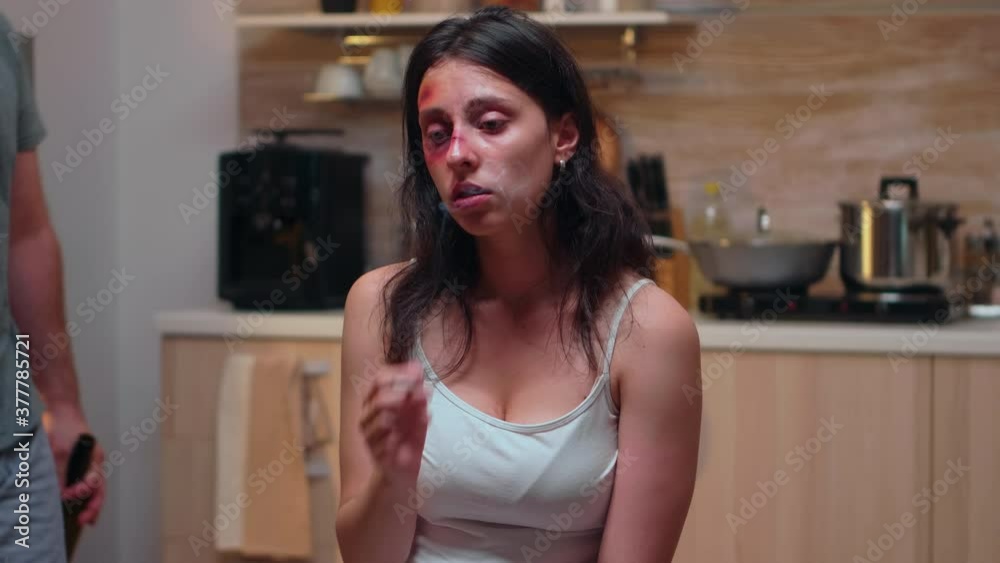 Portrait of abused wife smoking in the kitchen. Abused terrified beaten woman covered in bruises suffering injury from alcoholic violent brutal aggressive husband screaming. Portrait of abused wife smoking in the kitchen. Abused terrified beaten woman covered in bruises suffering injury from alcoholic violent brutal aggressive husband screaming.
