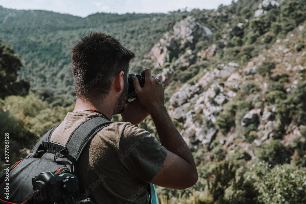 Joven explorador fotografo camina por medio de un valle seco en la naturaleza con su equipo fotografico Joven explorador fotografo camina por medio de un valle seco en la naturaleza con su equipo fotografico