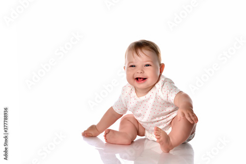 Happy laughing baby girl sitting on studio floor