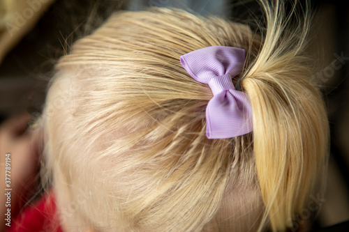 Close up and top down view of blonde toddler girl wearing purple bow