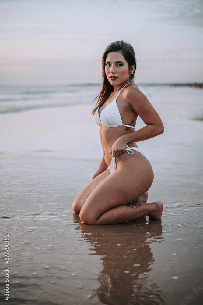 Chica veraniega morena en la playa naturaleza cañas de bambu con skateboard y bikini disfrutando de la hora dorada del atardecer
