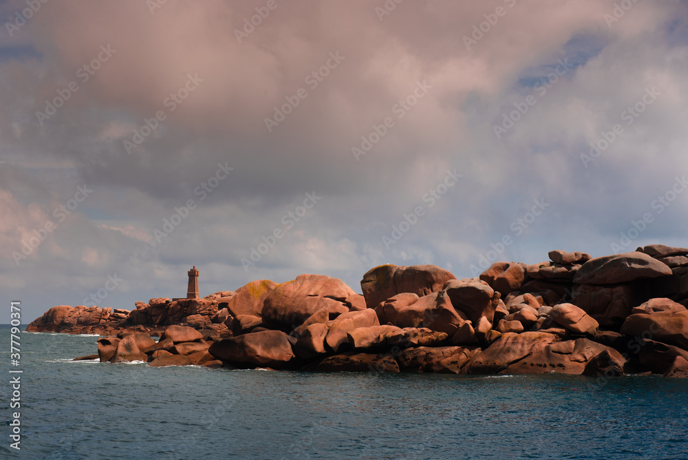 Men Ruz lighthouse and pink granit coast boulder in Brittany Men Ruz lighthouse and pink granit coast boulder in Brittany