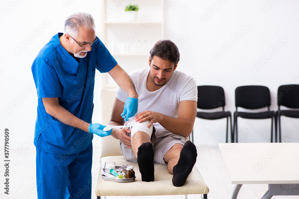 Fototapeta premium Leg injured man visiting old doctor in first aid concept