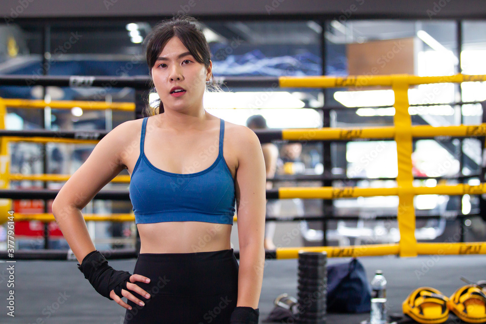 Cheerful Asian young woman workout in the gym by boxing training. 