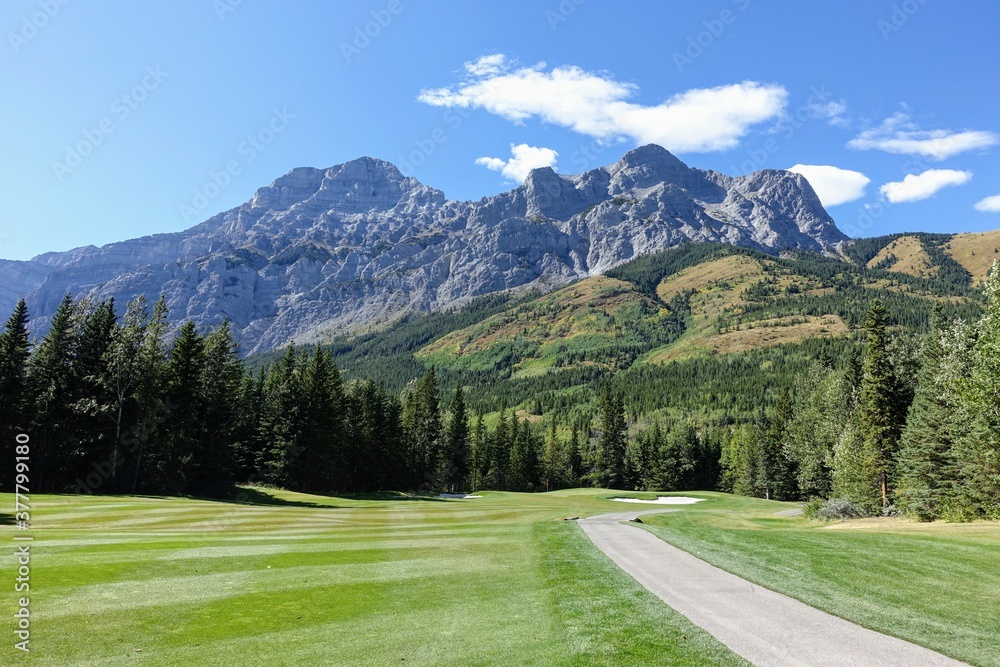 Gorgeous par 4 on a golf course surrounded by forest and big mountains in the background, on a beautiful sunny day in Kananaskis, Alberta, Canada.