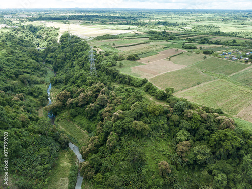 Aerial of an electric pylons running along a river gorge and undeveloped farmland in Dasmarinas Cavite.