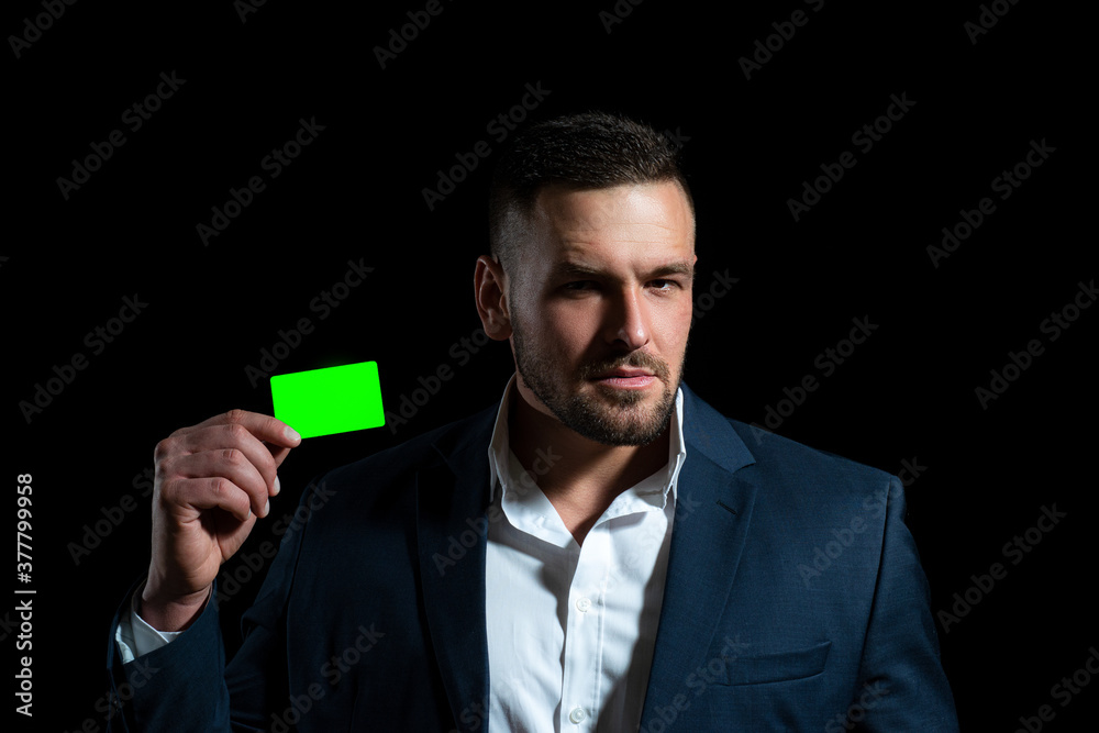 Businessman with a credit card. Portrait of a happy young business man holding debit card and isolated over black background. Businessman with a credit card. Portrait of a happy young business man holding debit card and isolated over black background.