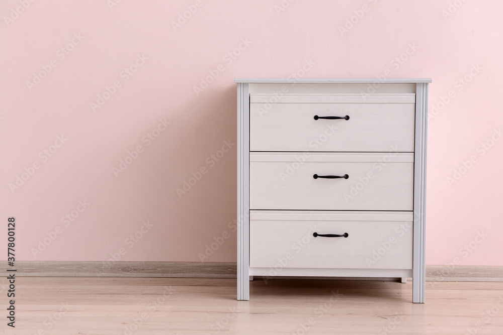 Modern chest of drawers near color wall in room Modern chest of drawers near color wall in room