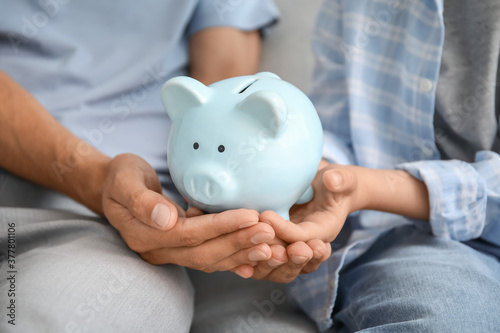 Family with piggy bank at home, closeup