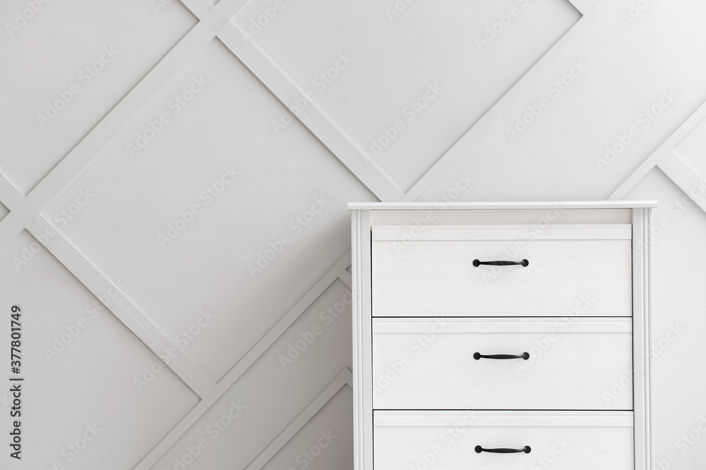Modern chest of drawers near grey wall in room Modern chest of drawers near grey wall in room