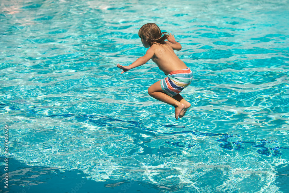 Child jumping in swimming pool. Kid having fun on summer vacation.