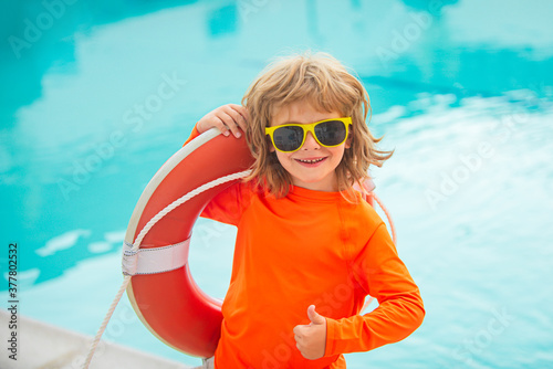 Happy kids boy play in swim guard or lifeguard in the sea. Funny child boy with lifebuoy show thumbs up sign.
