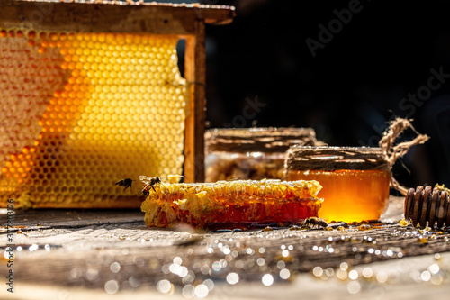 Honey in glass bowl, wooden honey dipper and honeycombs with honey on wooden table on background honeycombs with full cells of honey. organic natural ingredients concept