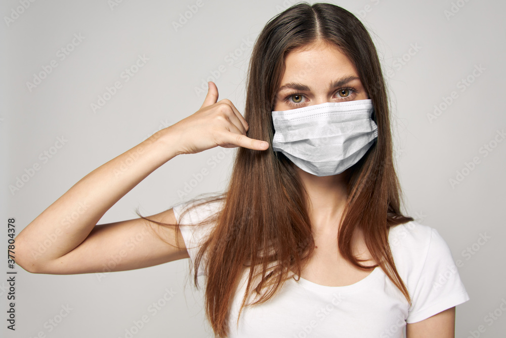 A woman in a medical mask on her face holds a hand near her head A woman in a medical mask on her face holds a hand near her head