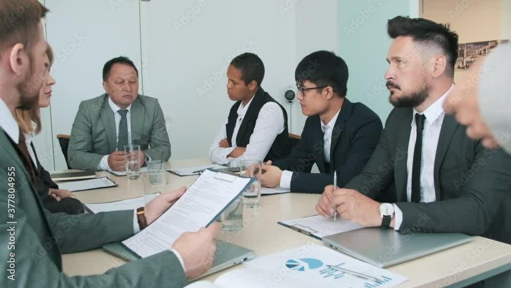 Multi-ethnic group of business people working together on new contract during meeting in office board room Multi-ethnic group of business people working together on new contract during meeting in office board room