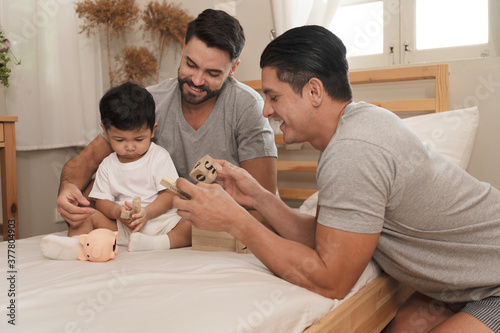 Young married LGBT parent couples play with adopted child in bedroom
