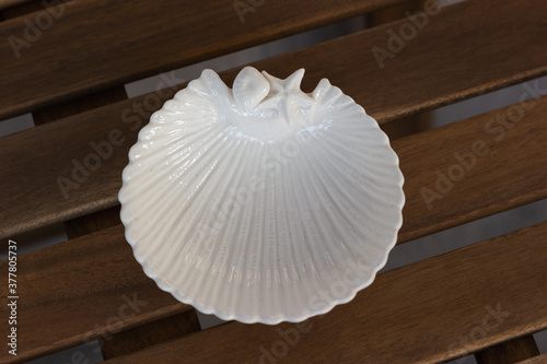 Close-up of a white plate in the form of a seashell on a wooden garden table