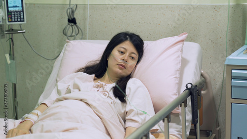 view form medical partition taiwanese female in vegetative state resting alone on bed in bright hospital.