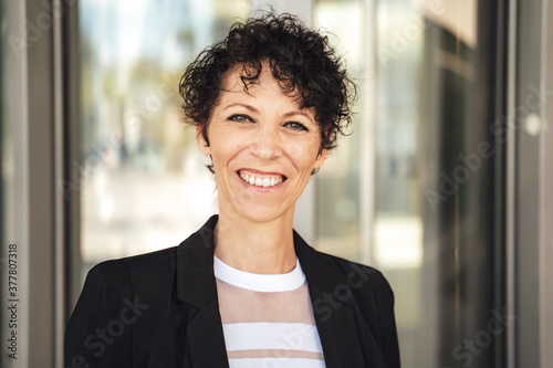 Close up portrait of smiling mature business woman in suit standing outside office