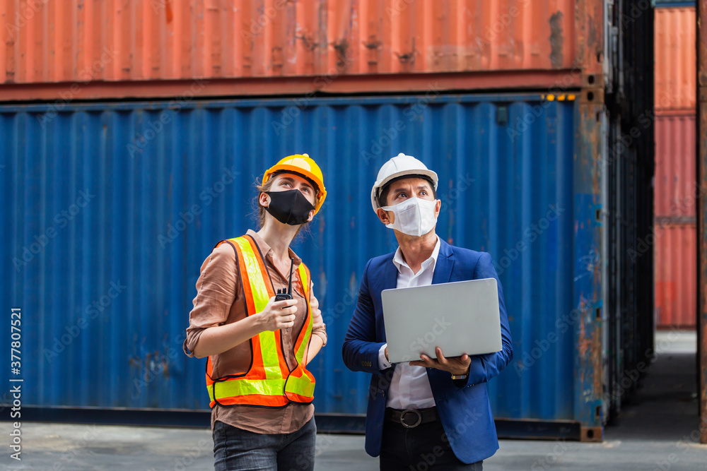 Engineer and worker team wearing protection face mask against coronavirus checking containers box from cargo, Logistic and teamwork concept Engineer and worker team wearing protection face mask against coronavirus checking containers box from cargo, Logistic and teamwork concept