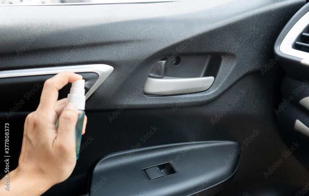 Close up of female hand spraying alcohol to car opener for disinfecting. Cleaning surfaces that are frequently touched area during Corona virus, COVID-19. Close up of female hand spraying alcohol to car opener for disinfecting. Cleaning surfaces that are frequently touched area during Corona virus, COVID-19.