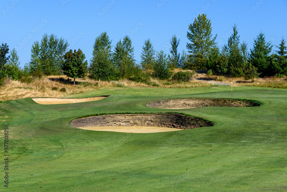 Three sand traps on a golf course guarding the green, sunny day with blue sky
Three sand traps on a golf course guarding the green, sunny day with blue sky