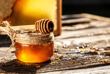 Honey dripping from a wooden honey dipper in a jar on wooden rustic background. honeycombs with full cells of honey. banner, menu, recipe, place for text