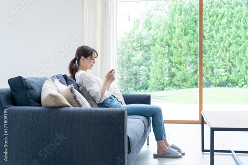 家で携帯を触るアジア人女性  © ponta1414