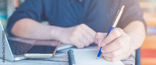 Obraz na płótnie Woman is writing on a notebook with a pen and she is using a mobile phone in the office. w salonie