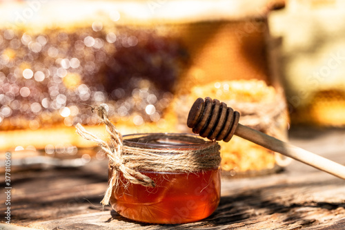 aromatic honey into jar on wooden table. bee products by organic natural ingredients concept, closeup