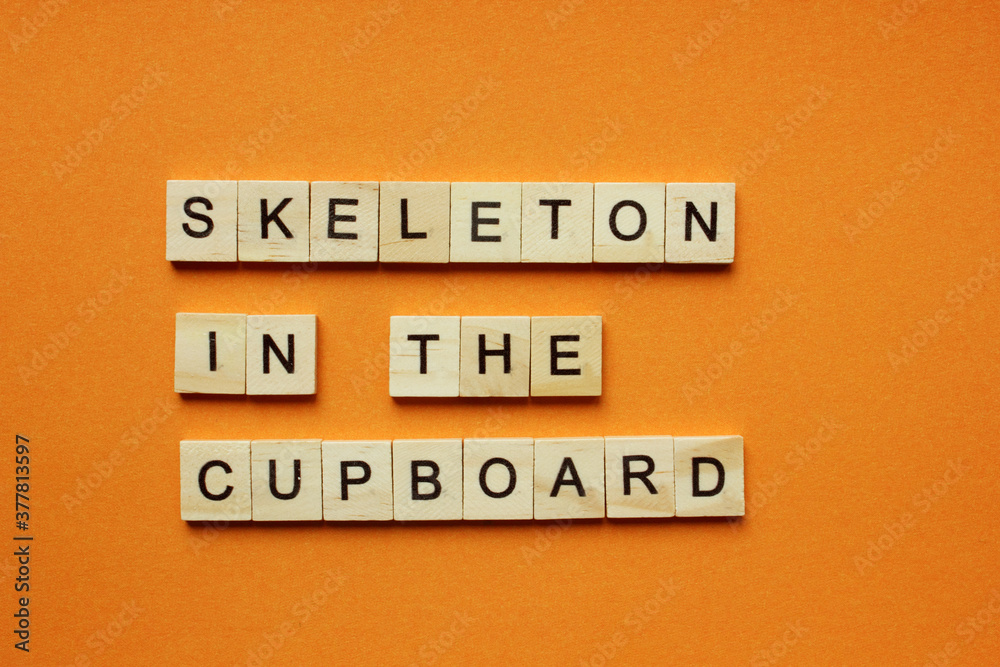 Words Skeleton in the Cupboard. Wooden blocks with an inscription on an orange background. Bulletin board. The concept of the holiday is Halloween. The view from the top. Copy space